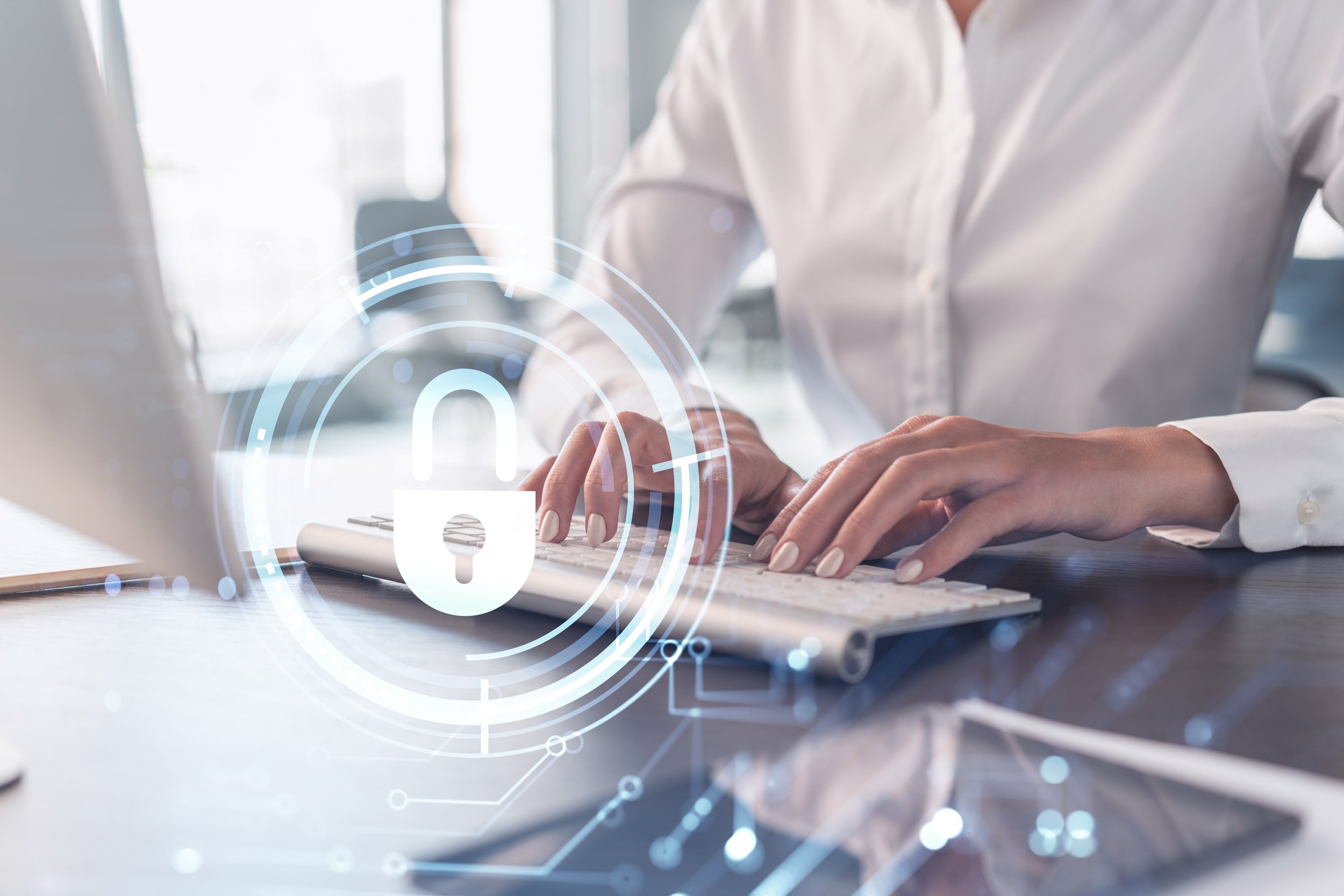 A woman programmer is typing a code on computer to protect a cyber security from hacker attacks and save clients confidential data. Padlock Hologram icons over the typing hands. Formal wear.